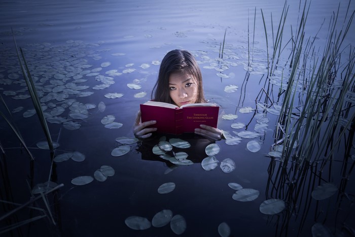 Asian woman reading a book in a lake