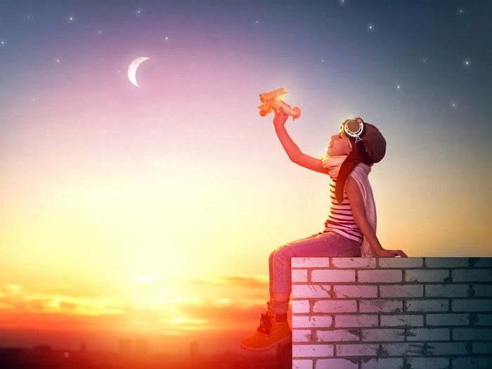 Girl with toy airplane at sunset