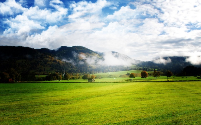 Green field with mountains and clouds