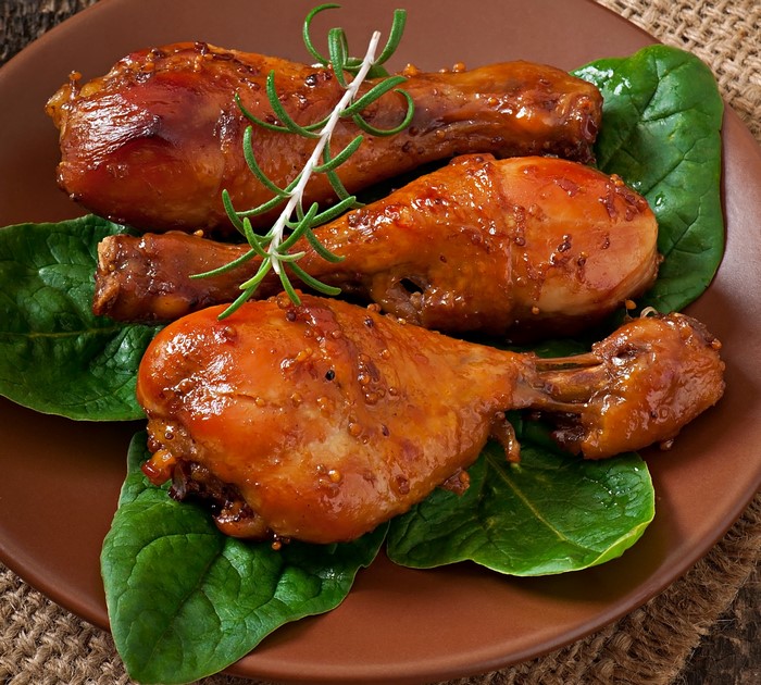 Three glazed chicken drumsticks with rosemary and spinach