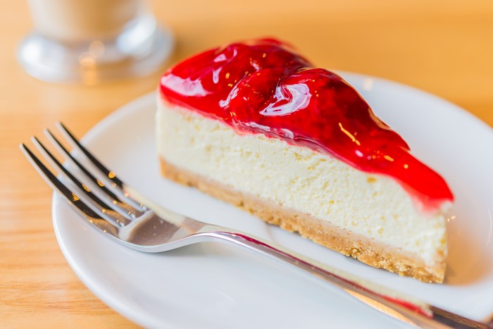 Slice of cheesecake with strawberry topping and fork