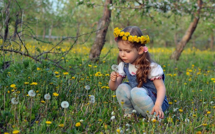 Girl with dandelion crown in a field of dandelions