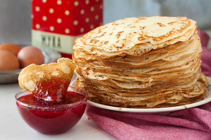 Stack of pancakes with jam and eggs