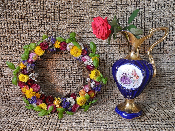 Still life with dried flower wreath and rose in a jug