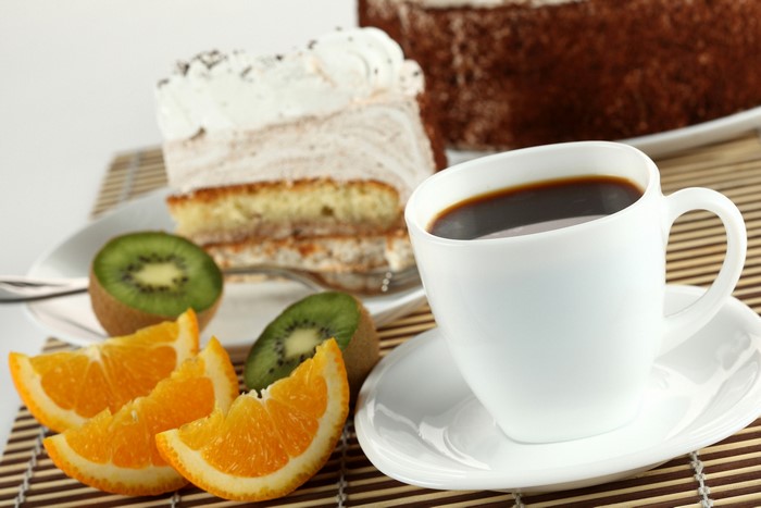 Coffee cup with cake, oranges, and kiwi