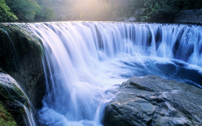 Waterfall cascading over rocks with trees in background