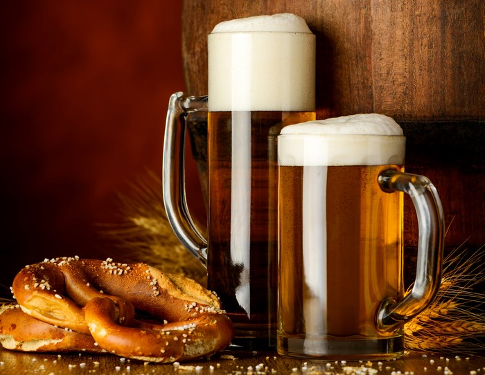 Two Mugs of Beer with Pretzels and Barrel