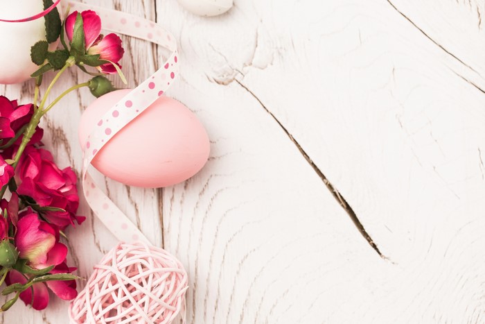 Easter eggs and pink roses on a wooden table