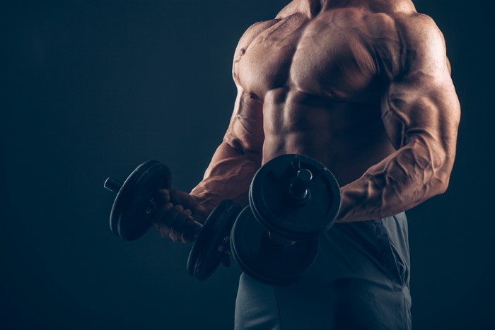 Muscular man lifting dumbbells