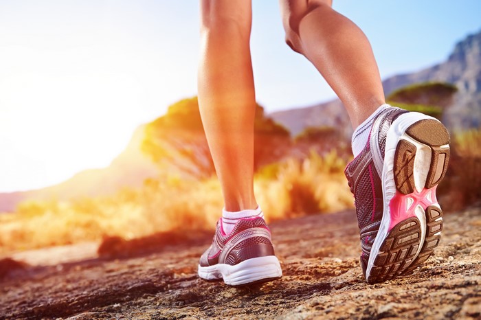 Close-up of runner's legs and athletic shoes on rocky terrain