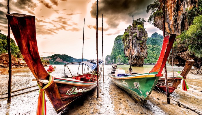 Longtail boats on a muddy shore in Phang Nga Province, Thailand