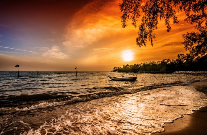 Sunset over the sea with a boat and flags