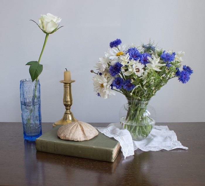 Still-life with white rose, wildflowers, candle, and book