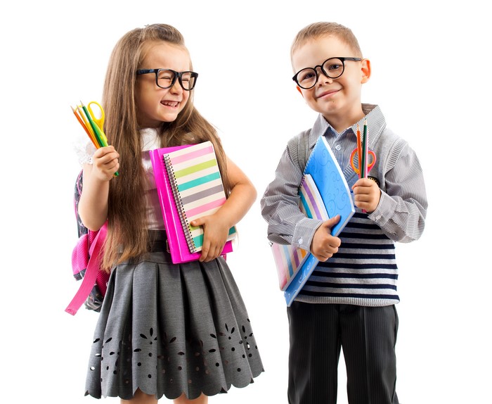 Two children with glasses, notebooks, and pencils