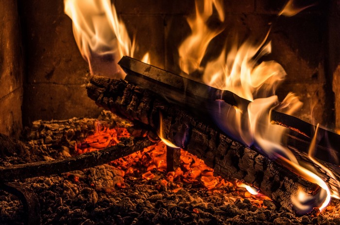 Close-up of a roaring fire with burning logs and glowing embers