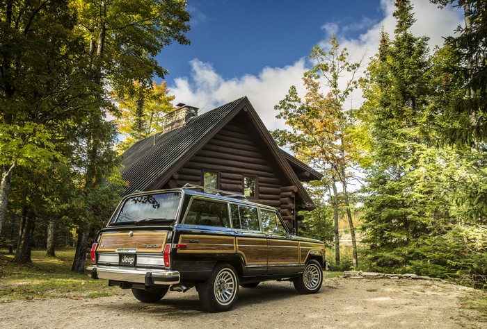 4K Jeep Wagoneer in front of log cabin