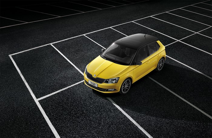 Yellow Skoda Fabia parked on asphalt with white lines