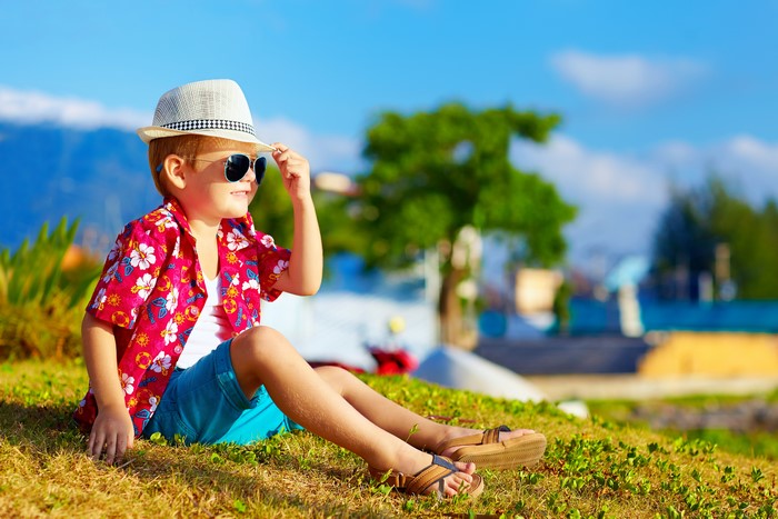 Boy in Hawaiian shirt and hat on grass