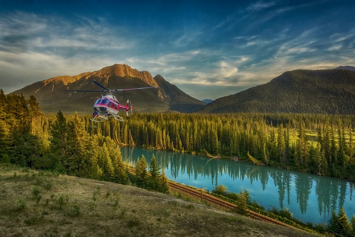 Helicopter flying over Bow River and forest in Canada