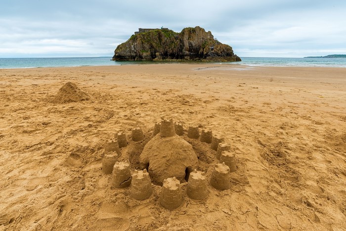Sandcastle on a beach with a rocky island in the sea