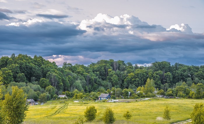 Village nestled in a forest under dramatic clouds