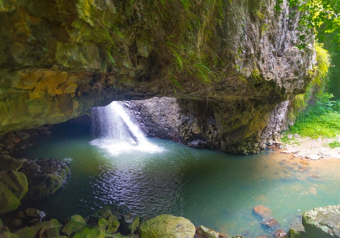 Waterfall cascading into a pool under a rock overhang