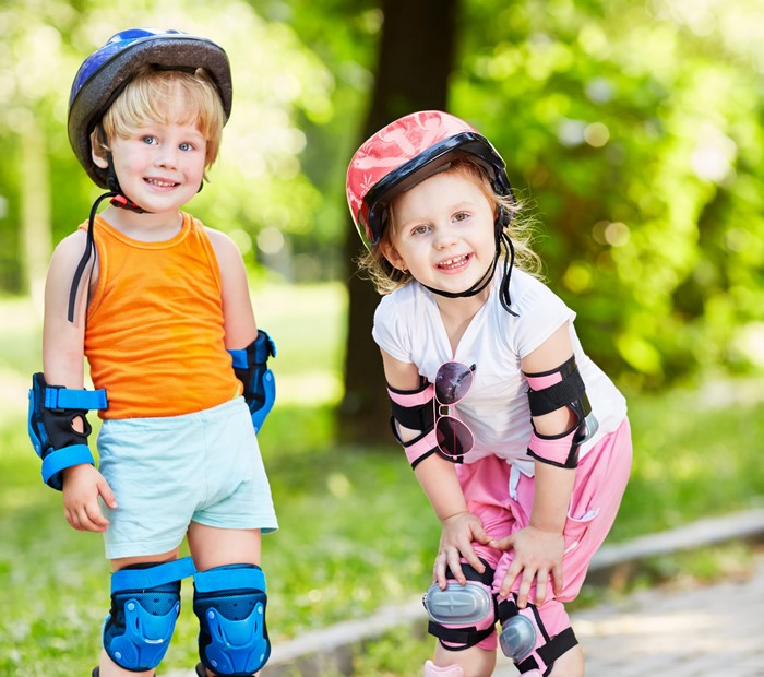 Two children wearing helmets and protective gear