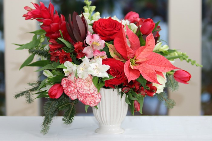 Red and pink floral arrangement with poinsettias and roses