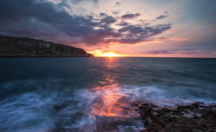 Sunset over the sea with rocky shore