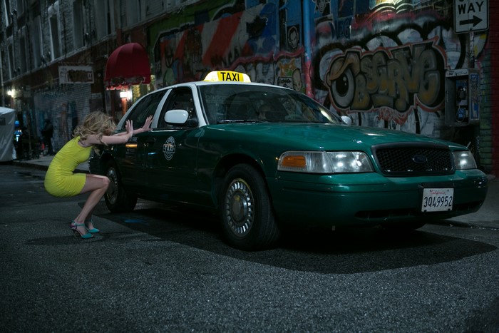 Woman pushing a taxi on a street