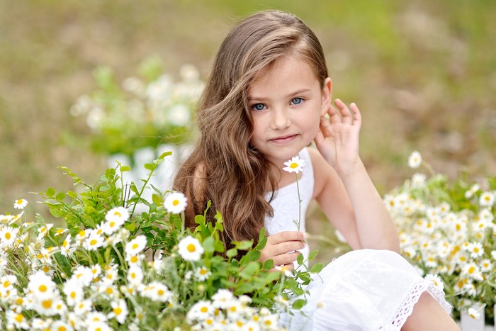 Young girl with blue eyes holding a daisy