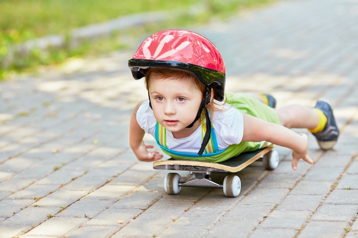 Girl in helmet on skateboard on pavement