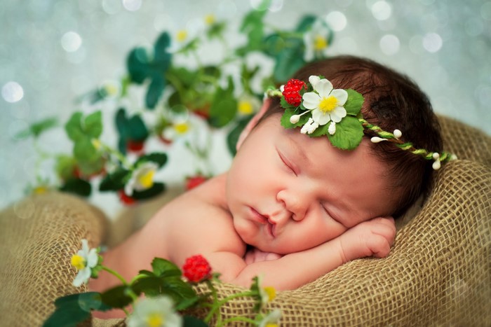 Newborn baby sleeping with strawberry flower crown