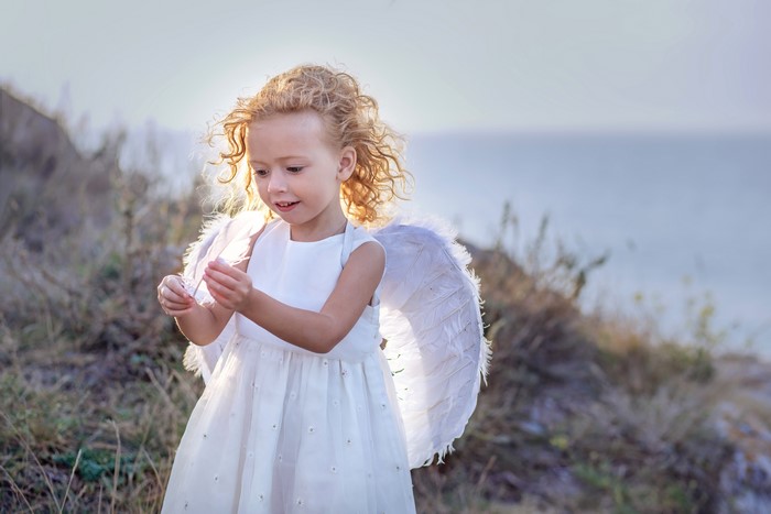 Little girl with angel wings in a white dress