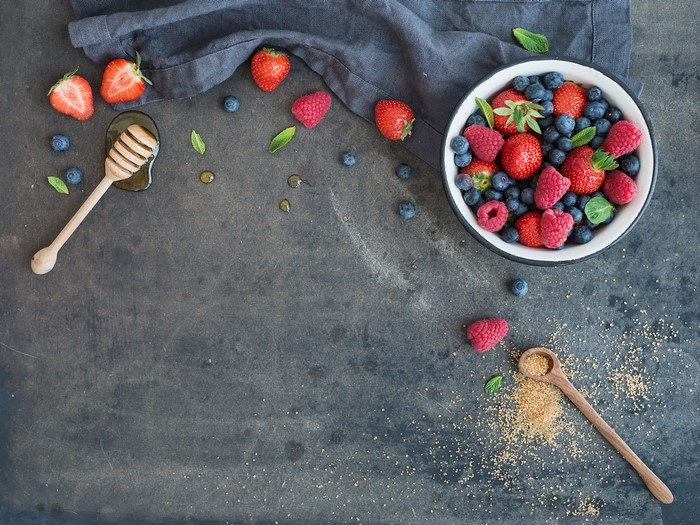Berries and honey on a dark surface