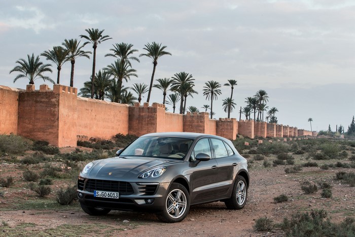 Porsche Macan S in front of a wall with palm trees