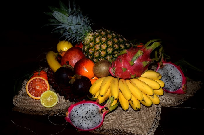 Fruit basket with pineapple, bananas, dragon fruit, kiwi, pomegranate, oranges, mangosteen, and lemon