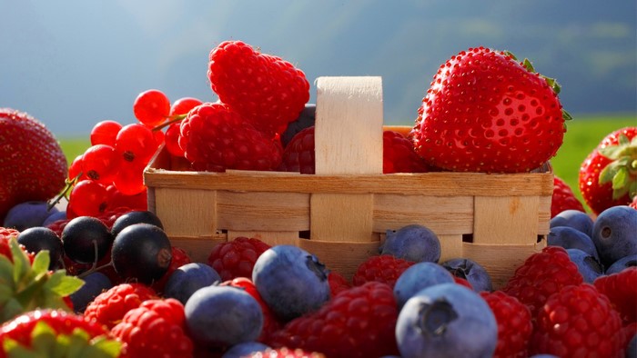 Basket of fresh berries including strawberries, raspberries, blueberries, and red currants