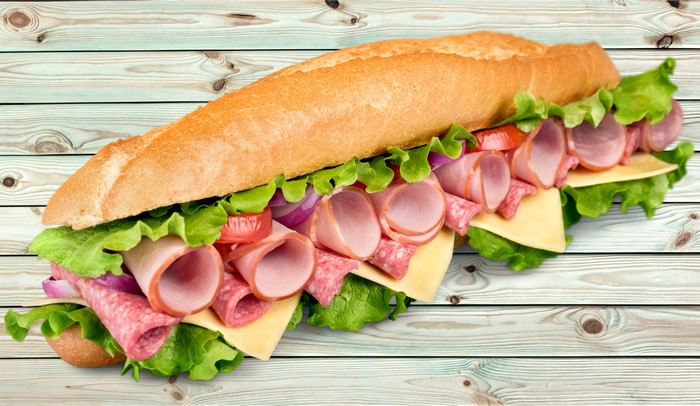 Submarine sandwich with ham, salami, cheese, lettuce, tomato, and onion