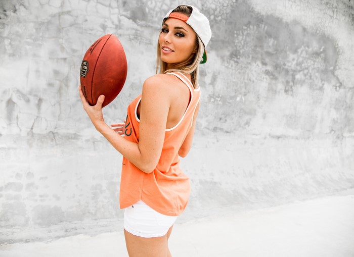 Woman in baseball cap holding American football