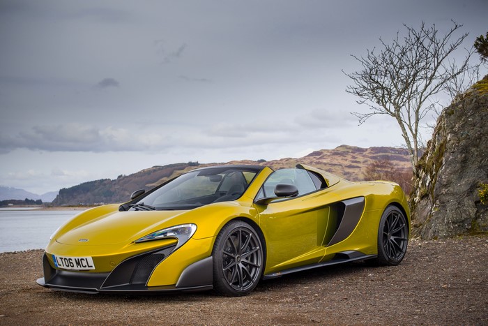 Yellow McLaren 675LT Spider parked by a rocky shore