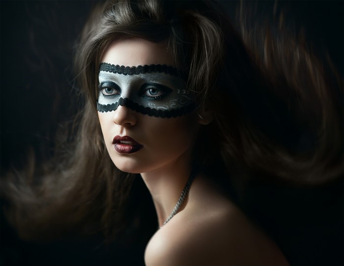 Woman wearing a black lace mask and dark lipstick