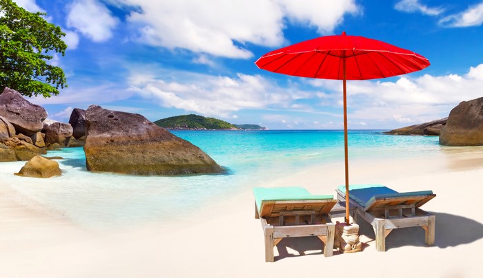 Beach with red umbrella and sunloungers in Thailand