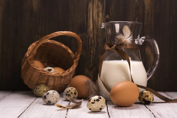 Milk and Eggs in Wicker Basket with Feathers