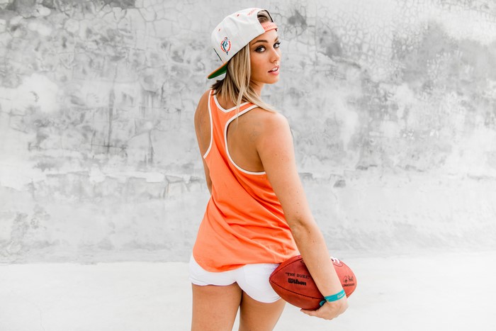 Woman in orange singlet holding American football