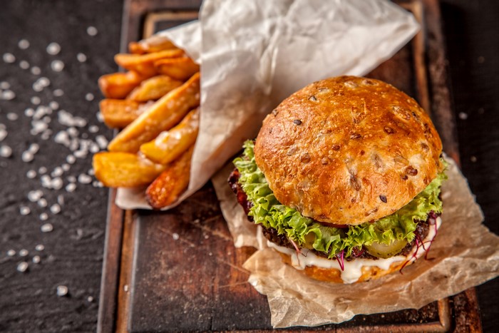 Hamburger and French fries on a wooden board