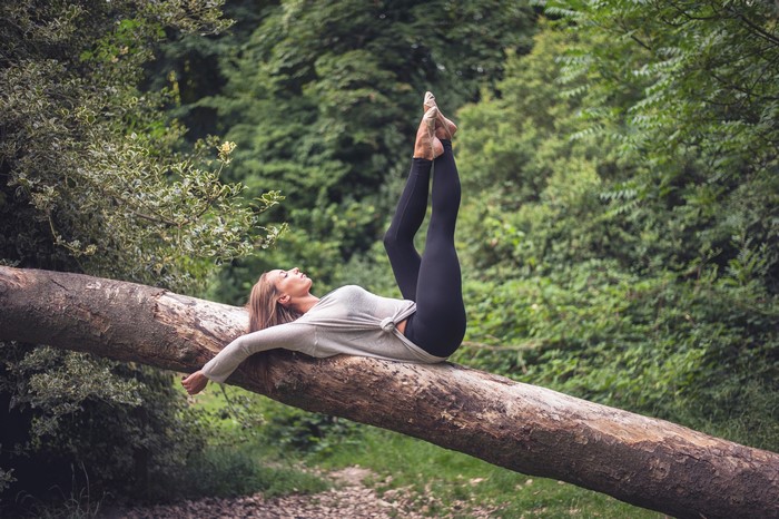 Woman doing yoga on a fallen tree trunk