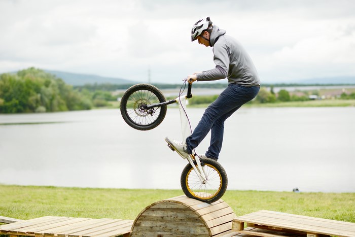 Man on Bicycle Performing a Wheelie on Wooden Obstacle