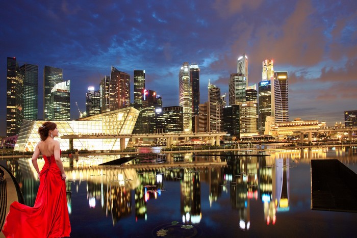 Woman in red dress with Singapore skyline at night