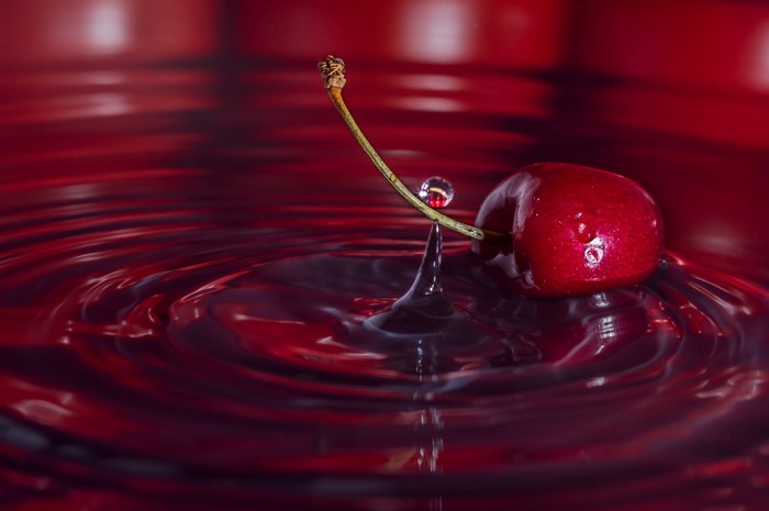 Cherry with water drop in red liquid
